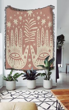 a living room filled with plants and a large tapestry hanging on the wall above it