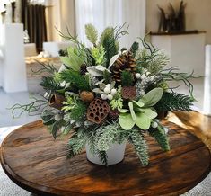 a vase filled with greenery and pine cones on top of a wooden coffee table