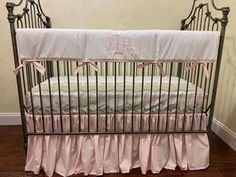 a baby crib with pink and white bedding in a room next to a wall