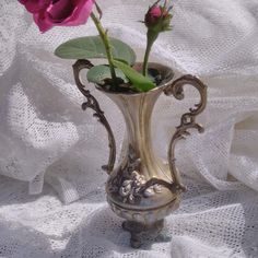 two pink roses in a silver vase on a white cloth