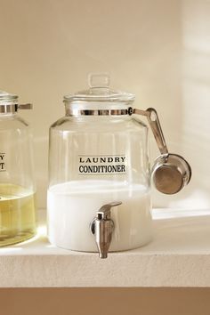 two glass containers sitting on top of a counter next to each other with liquid in them