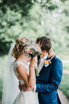 a bride and groom kissing in front of trees