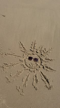 a smiley face drawn in the sand with sunglasses