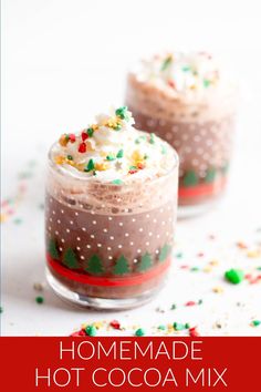 two glasses filled with hot cocoa and sprinkles on top of a table