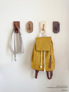 a yellow backpack hanging on the wall next to two hooks and a pair of scissors