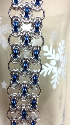 a silver chain with blue beads hanging from it's end and snowflakes in the background