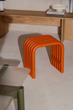 an orange bench sitting on top of a white floor next to a wooden table and chair