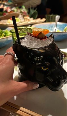 a hand holding a black cat shaped ice bucket