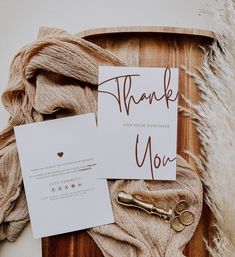 a thank you note and key on a wooden tray with some yarn next to it