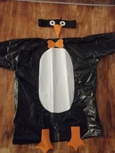 a penguin made out of plastic on top of a wooden table next to a black bag