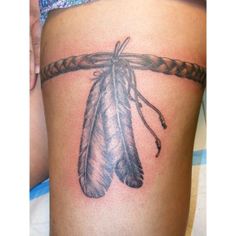 a tattoo on the back of a woman's thigh with a feather hanging from it