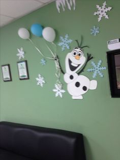 there is a green wall with some balloons and an image of the character from frozen world on it