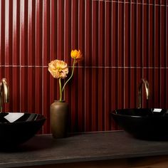 two black bowls with yellow flowers in them on a counter next to a red wall