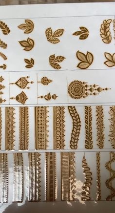 several different types of hendi tattoos on display in a store window with gold foil