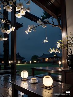 a table with two tea cups and saucers on it in front of an open window