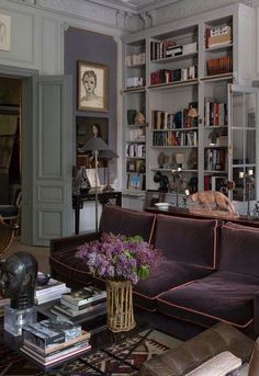 a living room filled with lots of furniture and bookshelves covered in shelves full of books