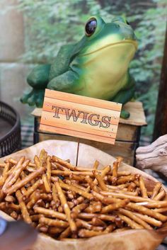 a frog sitting on top of a table next to a bowl filled with french fries