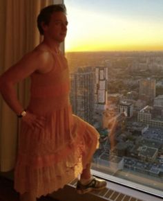 a woman standing in front of a window overlooking a city