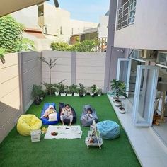 some people are sitting in bean bags on the grass by an apartment's patio