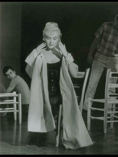 an old black and white photo of a woman standing in front of a man sitting at a table