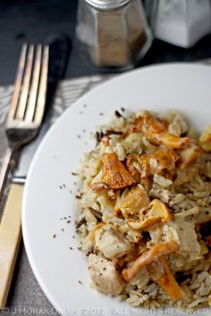 a white plate topped with chicken and rice next to a fork, knife and spoon