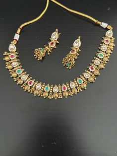 Beautiful gold choker set.  Available in 2 patterns:  green and gold. this has  high quality emeralds with intricate handcrafted gold in an attractive pattern.  multi color : this has kundan, rubies snd emeralds with gold in a choker style.  Earrings are dangle and drop with jhumka bottoms but are light.  Made from silver alloy with gold polish. Gold-plated Green Kundan Necklace With Meenakari, Green Kundan Necklace With Meenakari In Gold Plated, Green Kundan Necklace With Meenakari Detail, Green Gold Plated Kundan Necklace For Festivals, Green Gold-plated Kundan Necklace For Festivals, Gold Plated Green Jewelry For Diwali, Green Gold Plated Jewelry For Diwali, Green Gold Plated Bollywood Necklace, Gold Emerald Necklace With Meenakari Kundan