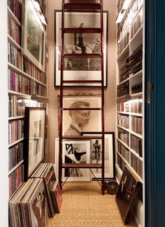 a room filled with lots of books and pictures on the wall next to a ladder