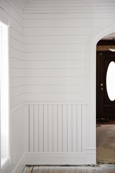 an empty room with white walls and wood flooring in the foreground, through which there is a door to another room