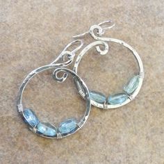 "Hammered Sterling Silver Hoop Earrings with Aquamarine Nuggets, 1.25\" Diam. - Hammered Hoops - Artisan Hoop Earrings These hammered artisan hoop earrings are created from a very heavy gauge sterling silver wire giving them a heft and depth not usually found in hoop earrings. Our signature \"loop-de-loop\" design on the top adds a simple, yet elegant, design detail while the hand hammered texture catches the light with artful subtlety. Sparkling, faceted, light blue aquamarine nuggets are wired Wire Fashion, Catherine Paiz, Metalsmithing Jewelry, Unusual Earrings, Earring Ideas, Hammered Sterling Silver, Sterling Silver Hoop Earrings, Wire Work, Wire Earrings