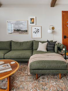 a living room with green couches and pictures on the wall above it's coffee table