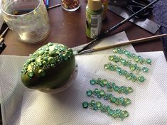 a table topped with lots of crafting supplies on top of a white napkin covered in green beads