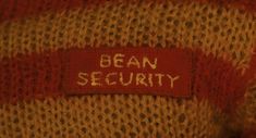 a red and white sweater with the word bean security on it's label is shown