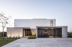 a car is parked in front of a modern house with large garage doors and windows