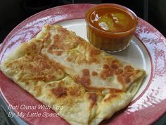 two flat breads on a plate with a cup of sauce