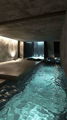 an indoor swimming pool with water flowing from the ceiling to the floor, and illuminated by lights on either side