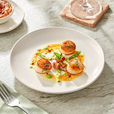 a white plate topped with scallops on top of a table