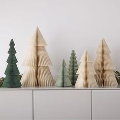 three wooden christmas trees sitting on top of a white table next to each other in front of a wall