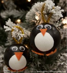 two penguin ornaments hanging from a christmas tree