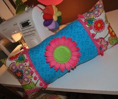 two colorful pillows sitting on top of a table next to a sewing machine and toy