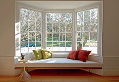 a white couch sitting in the middle of a living room next to a large window