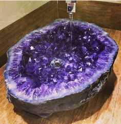 a purple rock with water spouting out of it's center and surrounded by other rocks