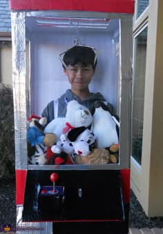 a boy in a box with stuffed animals on the front and inside, all dressed up