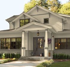 a white house with gray trim and black shutters on the front door is shown