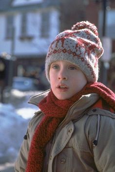 a young boy wearing a knitted hat and scarf in the snow with words written below