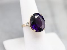 The focal point of this ring is absolutely the outstanding oval cut amethyst that we've set at the center. Bright sound cut diamonds light up the shoulders, bringing even more sparkle to this beautiful gem! Metal: 14K Yellow Gold Gem: Amethyst 13.59 Carats Gem Measurements: 17.3 x 13.2 mm, Oval Accents: 2 Diamonds totaling .26 Carats, I in Color, SI1 in Clarity Ring Size: 8