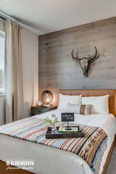 a bed room with a neatly made bed and a deer head mounted on the wall