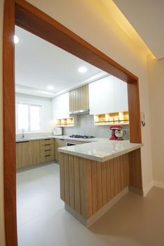 an empty kitchen with wooden cabinets and white counter tops is seen through the doorway to another room