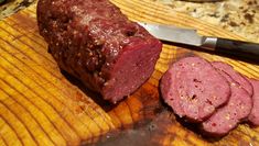 a large piece of meat sitting on top of a cutting board next to a knife