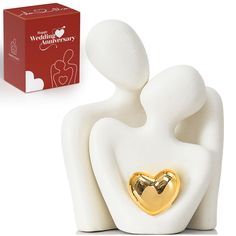 a white figurine with a gold heart on it next to a red box