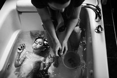 a woman washing a baby in a bathtub